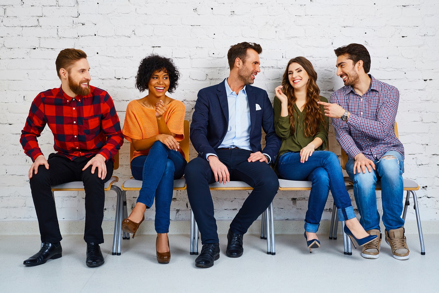 Professional people sitting on chairs by a wall 