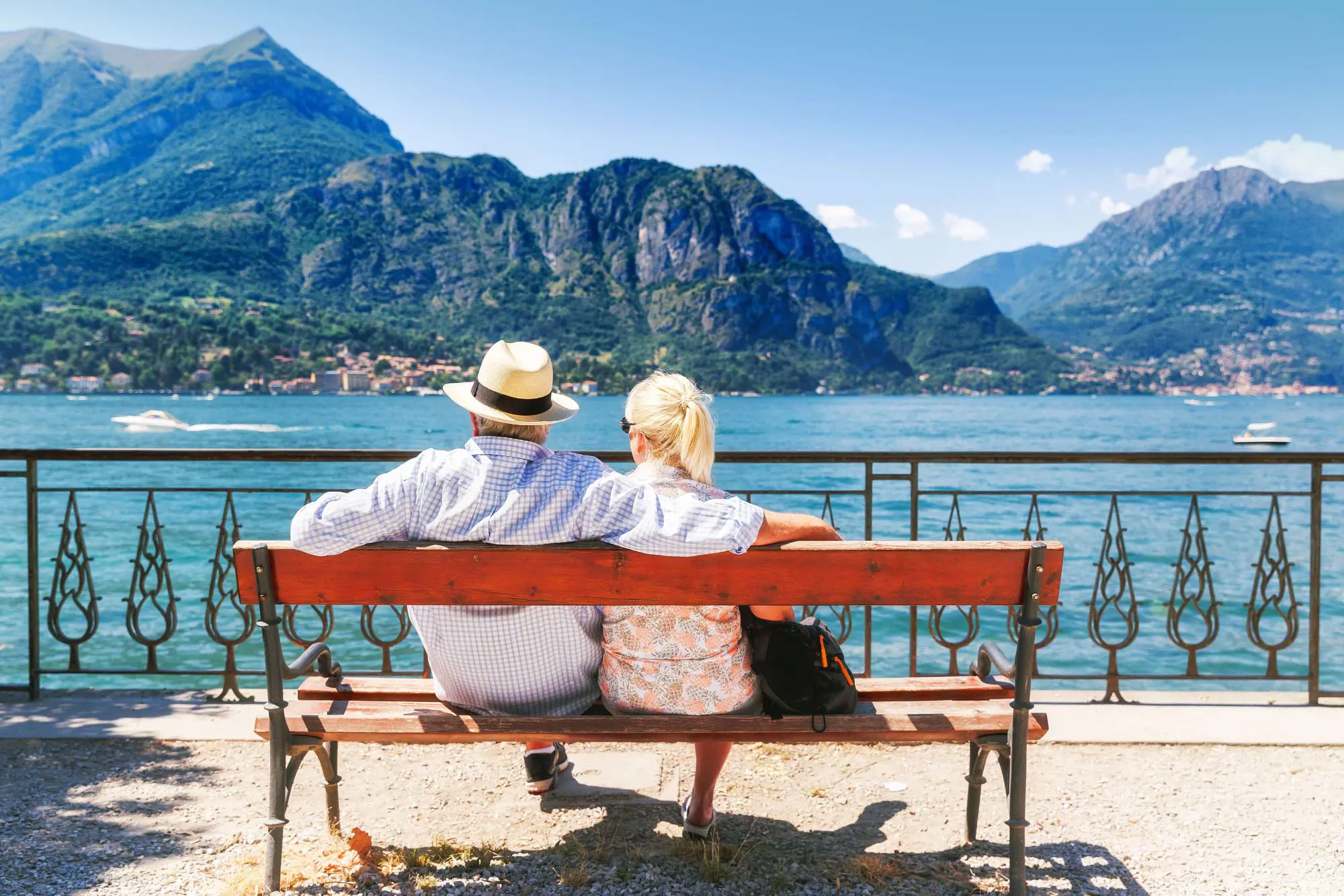 The back of a couple sat on a bench looking out to Lake Como