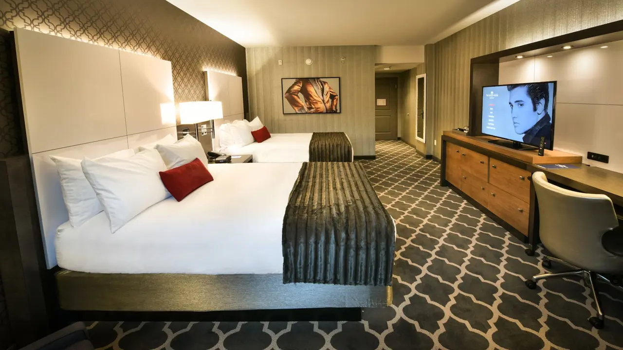 A queen room at The Guest House at Graceland with two queen beds, elegant furnishings, and warm lighting