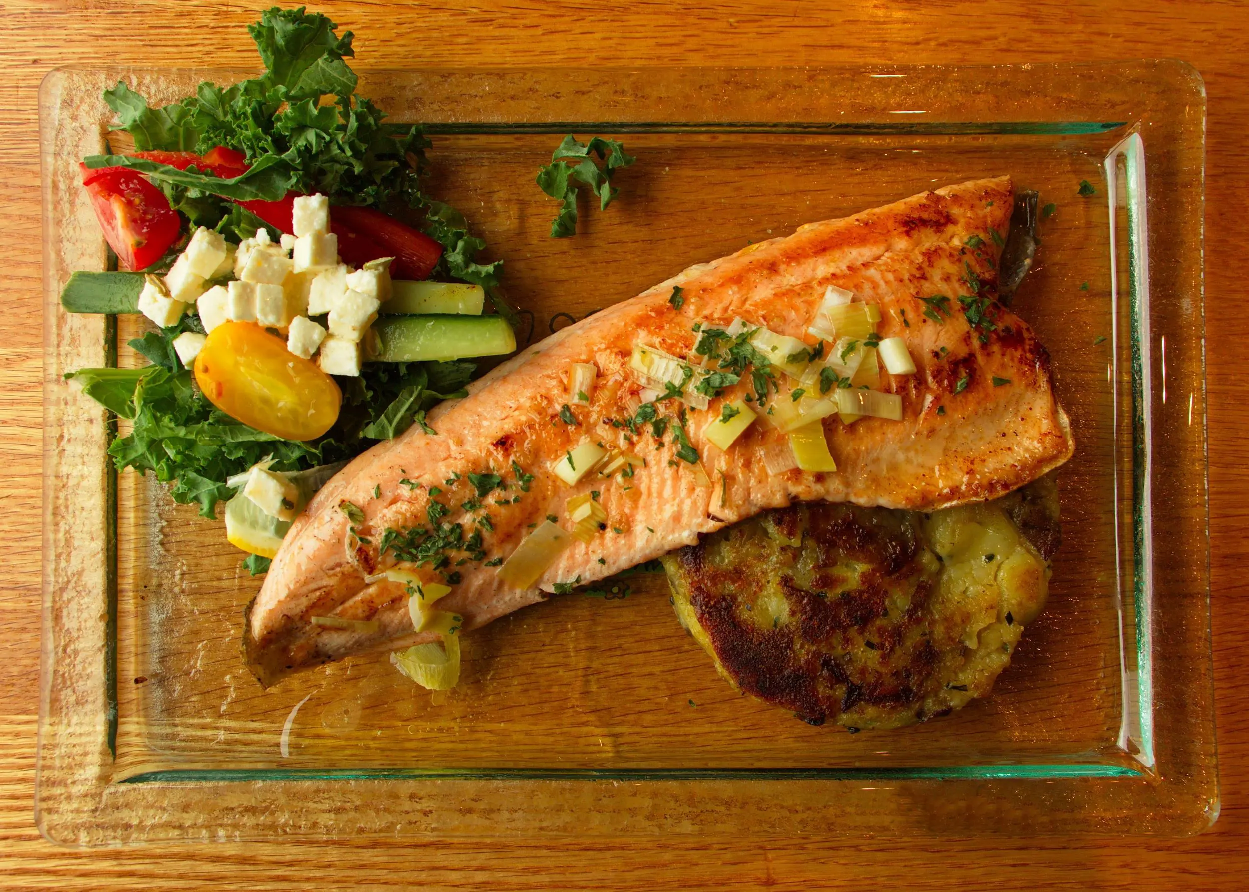 Board with dinner consisting of fish, a side salad and potato